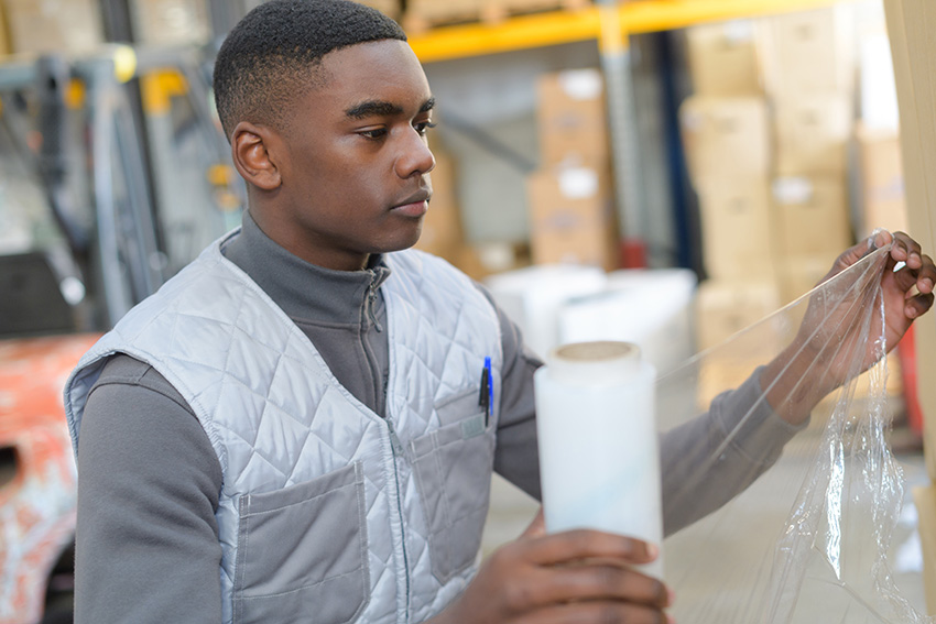 Employee Holding Shrink Wrap and Preparing Order