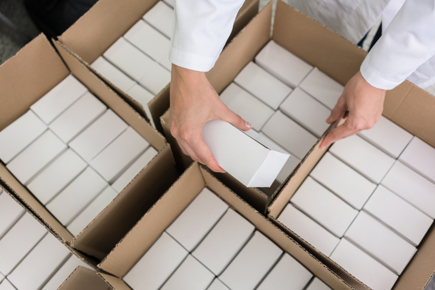 Employee Packing Smaller Boxes into Large Cardboard Box